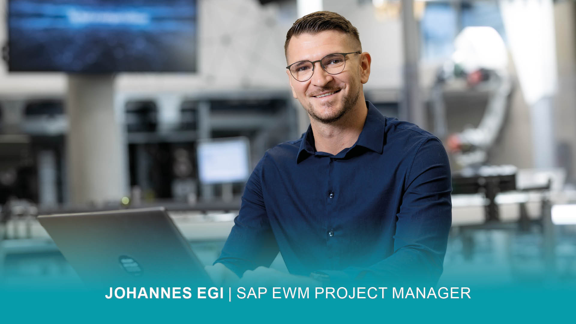 SAP EWM Project Manager Johannes sitzt arbeitend vor seinem Laptop und lächelt