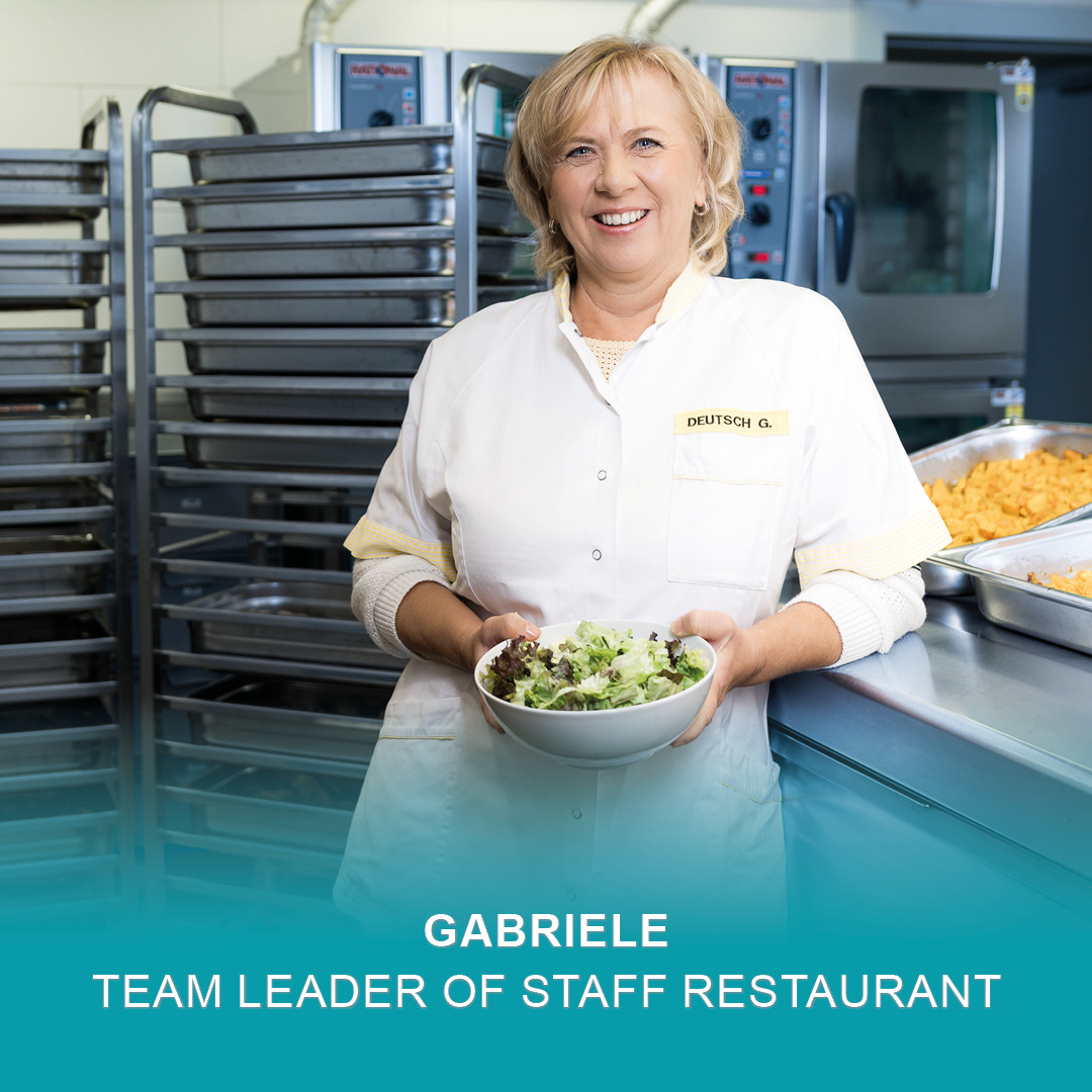 Gabriele tient une assiette de salade fraîche au restaurant de l'usine