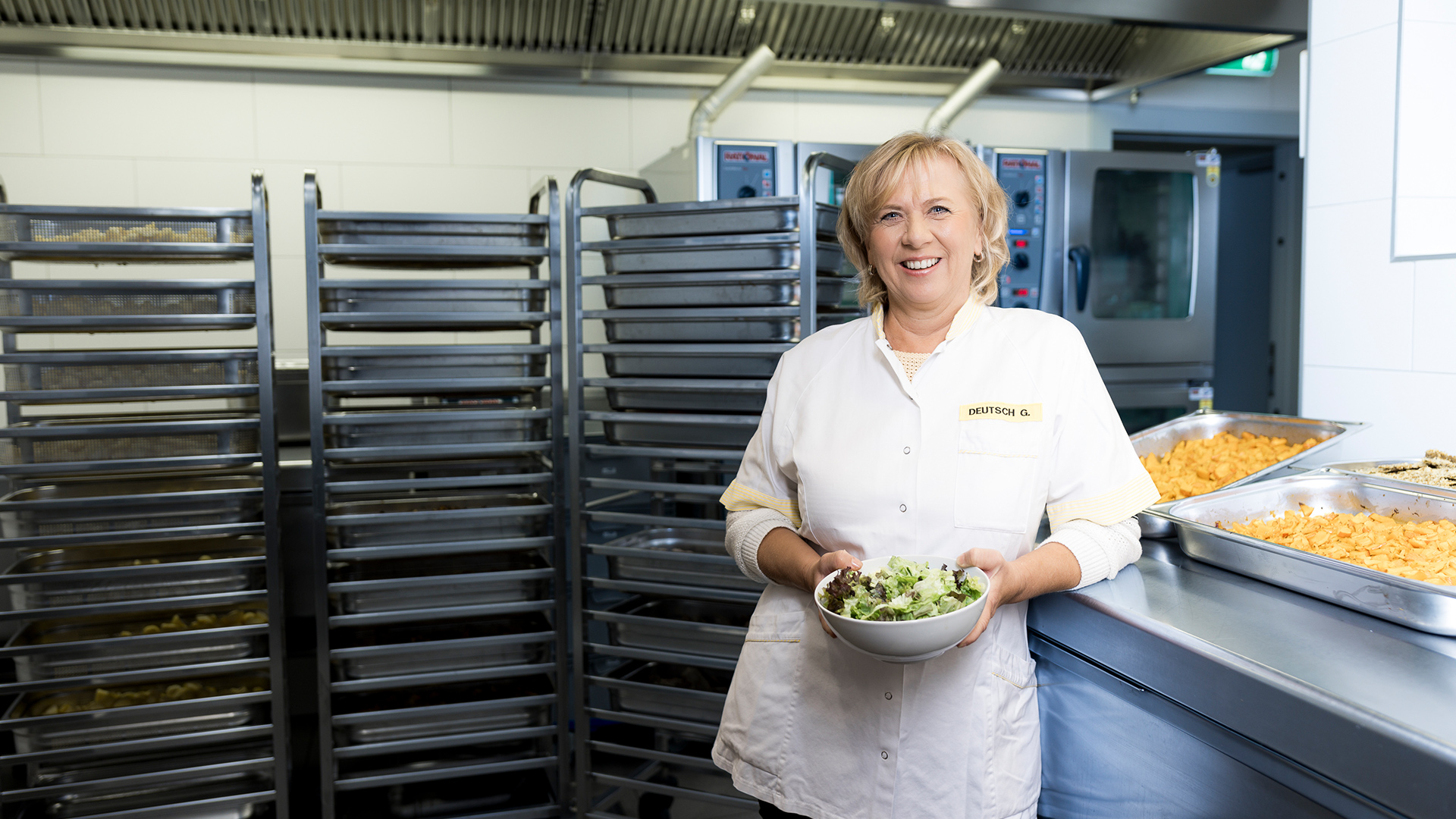 Gabriele tient une assiette de salade fraîche au restaurant de l'usine