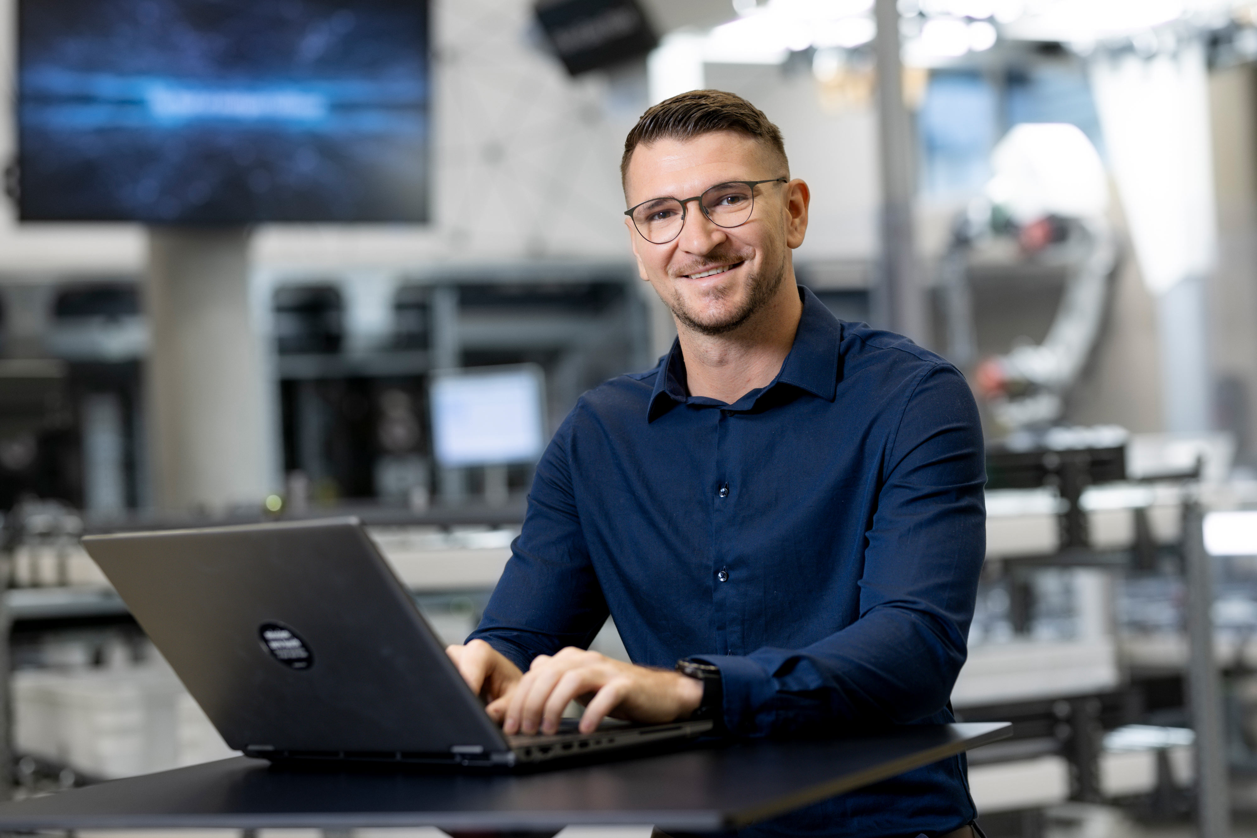 SAP EWM Project Manager Johannes sitzt arbeitend vor seinem Laptop und lächelt