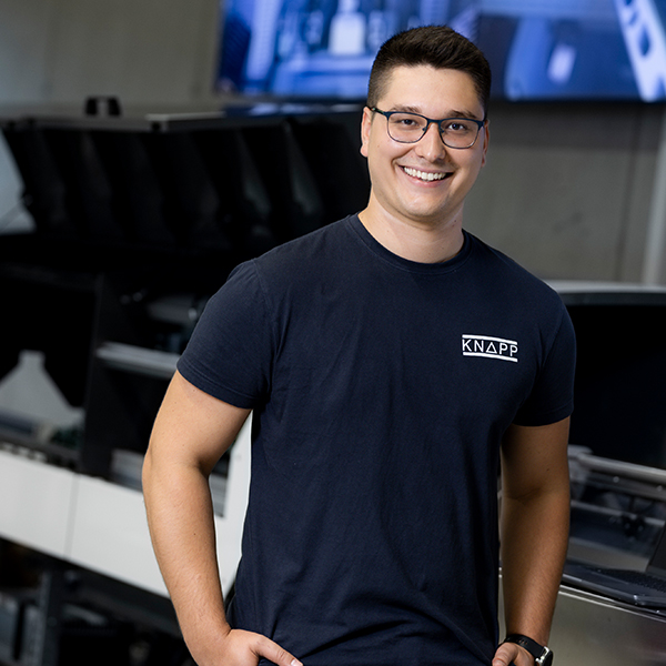 Karlo, técnico de puesta en marcha de software, sonríe con un portátil en el almacén